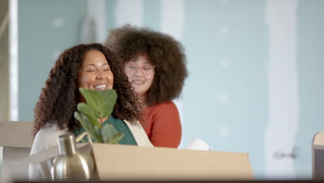 Casual-biracial-businesswomen-carrying-boxes-moving-into-office,-slow-motion-with-copy-space