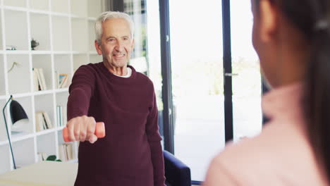 Senior-caucasian-man-converses-with-a-young-biracial-woman-at-home