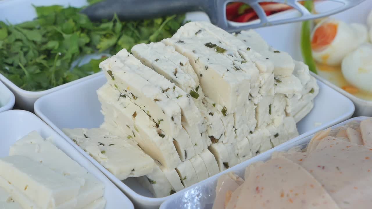 Skiveskåret ost med krydderurter, kogte æg og pålæg på en buffet