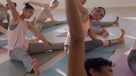 Clase-De-Yoga-De-Hermosas-Mujeres-Multiétnicas-Practican-Pose-De-Curvatura-Lateral-Sentada-Disfrutando-De-Un-Estilo-De-Vida-Saludable-Haciendo-Ejercicio-En-El-Gimnasio-Meditación-Grupal-Al-Amanecer