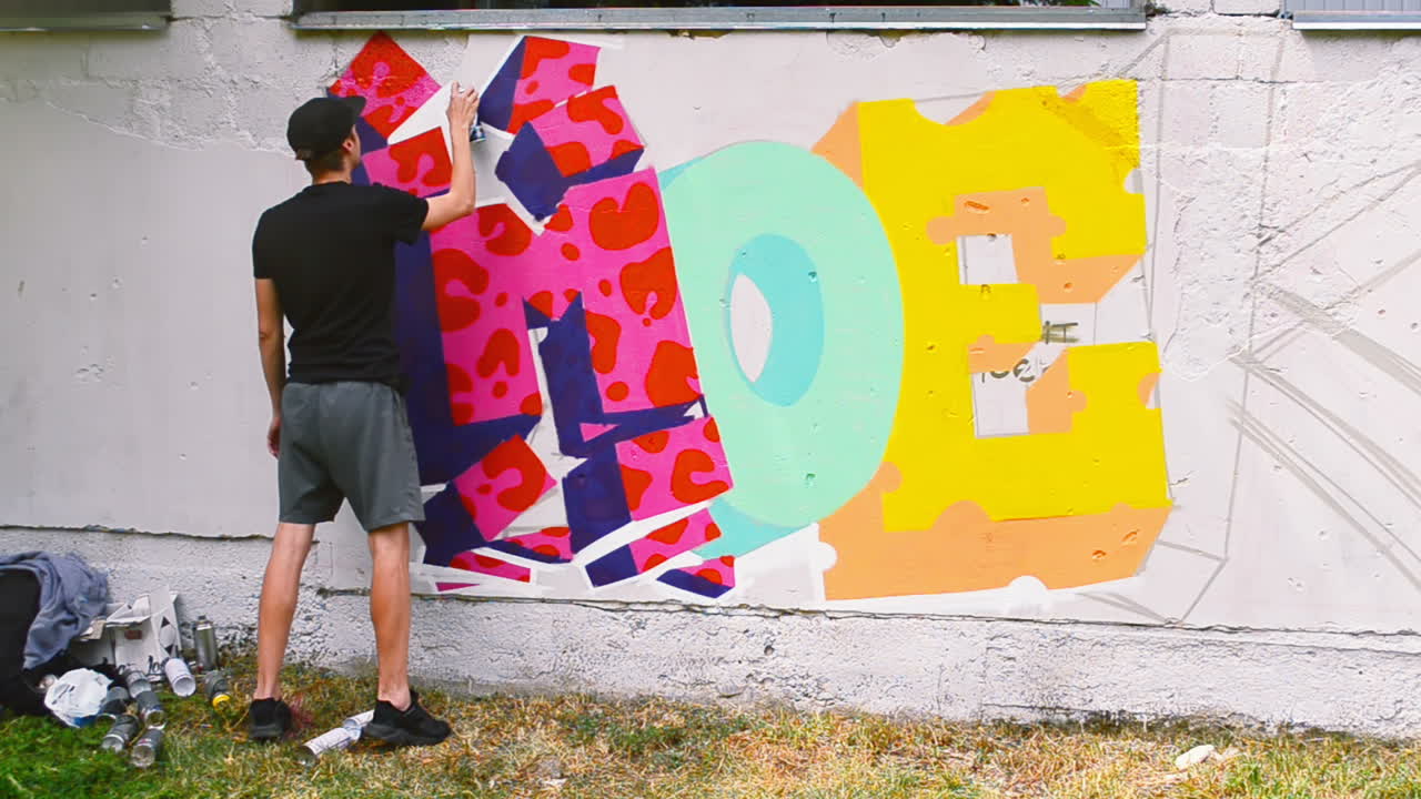 Kunstneren tegner graffiti på et gjerde. Abstrakt tegning.