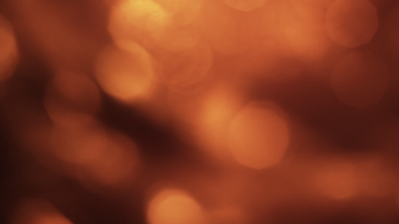 Sfondo astratto in movimento con luci bokeh arancioni calde.