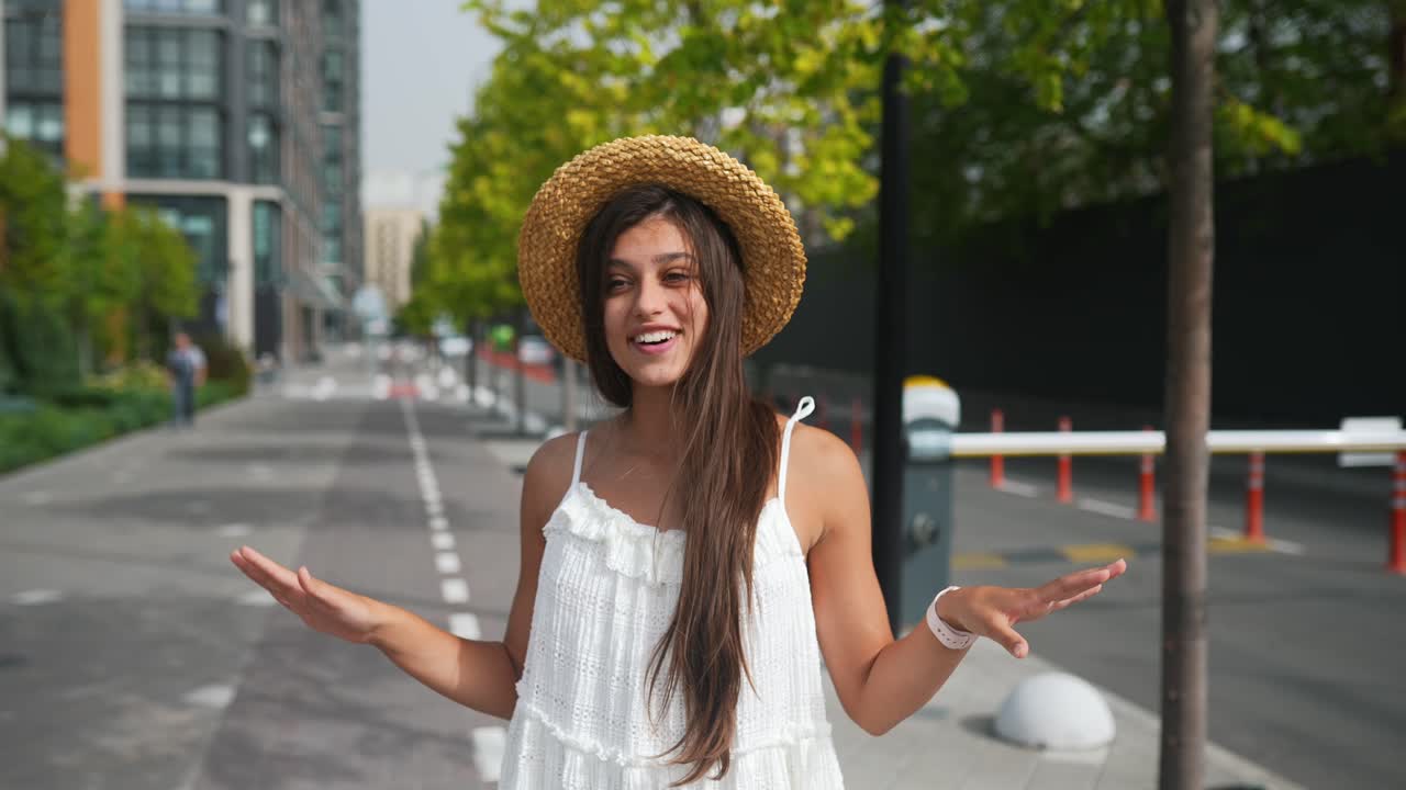 mujer con un sombrero de paja y un vestido blanco en una calle de la ciudad