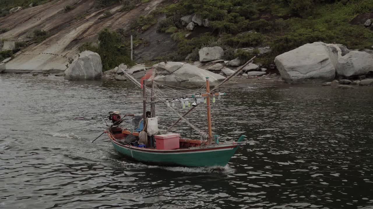 A local Thai Squid fisherman heading out of the harbour at Khao Takiab, his boat equipped with lights for night fishing as he heads out for the evening of fishing, Hua Hin, Thailand
