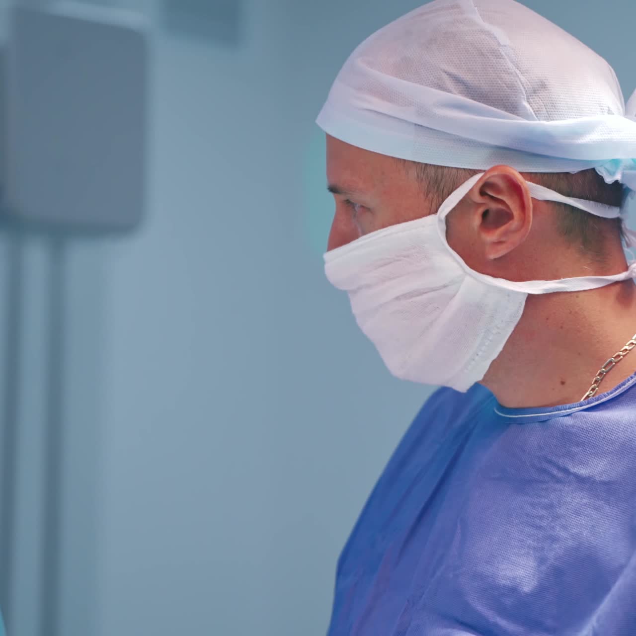 Portrait of a professional doctor during surgery. Male surgeons in blue medical uniform and masks in hospital. Close-up.
