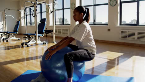 woman performing seated exercise on exercise ball in a therapy session