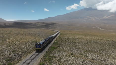 drone frontal view of a freight train transporting multiple mineral wagons across the peruvian andes.