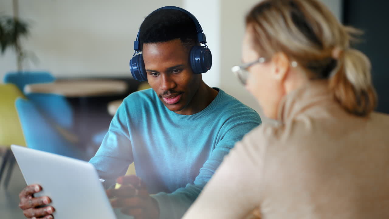 Young Black Man with Headphones Collaborating on Laptop with Woman