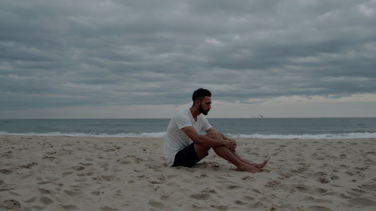 Man Sitting Alone on a Stormy Beach