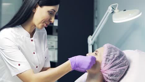 professional beautician consulting a patient about lips augmentation in the esthetic office. doctor examines the woman