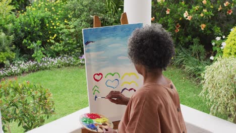 Vista-Trasera-De-Una-Mujer-Afroamericana-De-Alto-Rango-Pintando-Mientras-Estaba-De-Pie-En-El-Porche-De-La-Casa