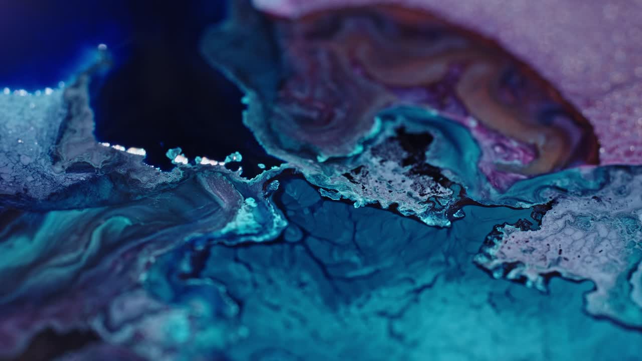 primer plano de tinta azul y rosa vibrante difundida en el agua, creando un patrón abstracto