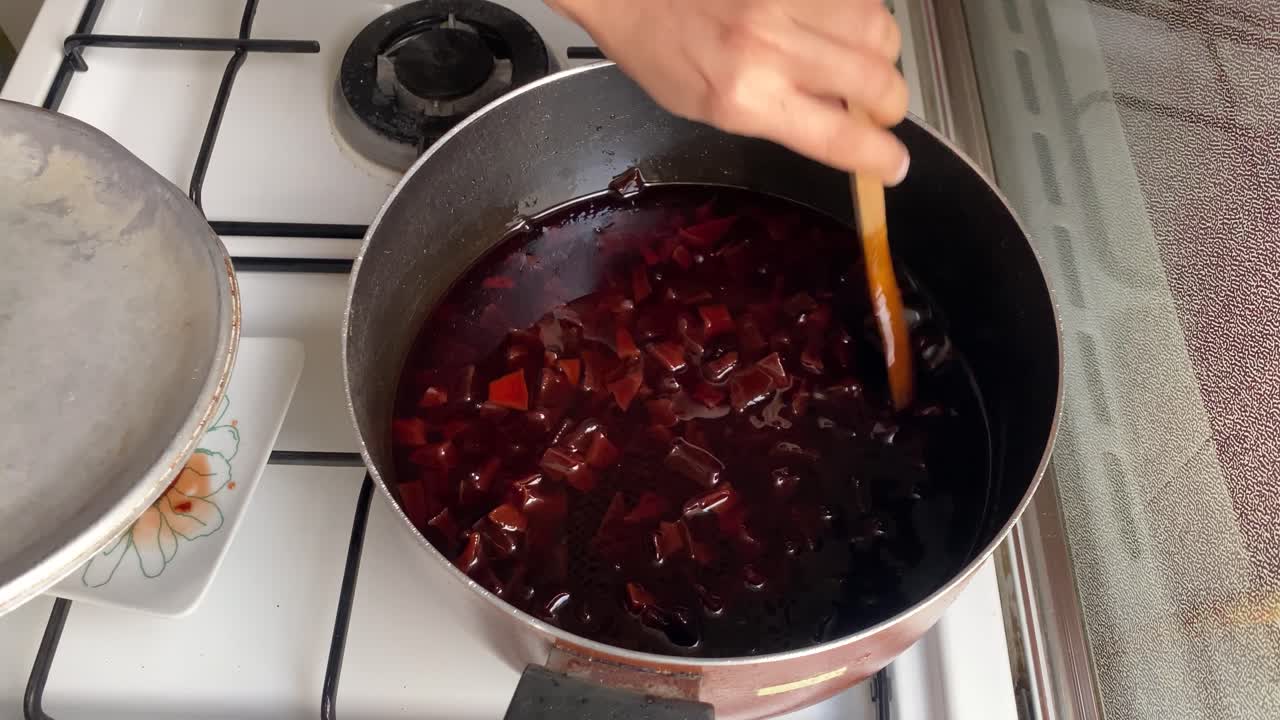 Slow food cooking at home red syrup for sweet quince jam stir and mix wild apple fruit slices to make delicious Persian cooking cuisine gourmet culinary dessert in a big city in Tehran urban life Iran
