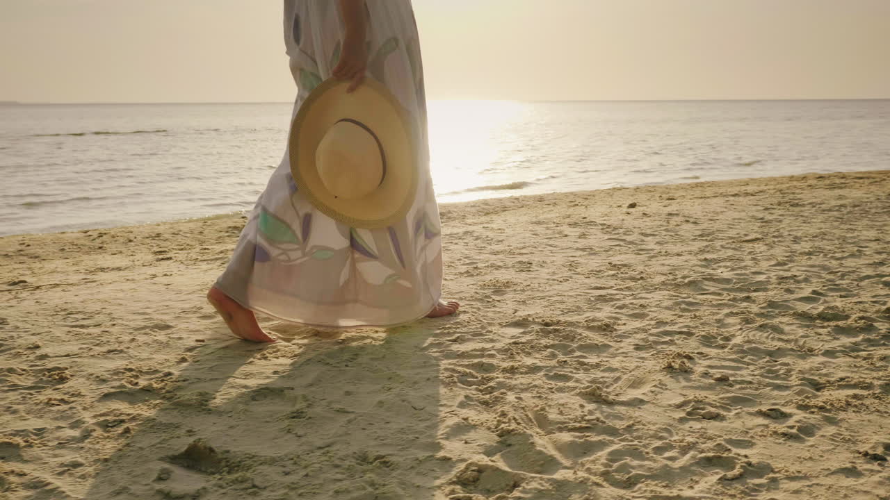 una pareja joven camina descalza sobre la arena de la playa en el marco solo se ven las piernas v