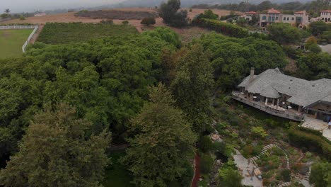 Tomando-Hacia-Atrás-Una-Toma-Aérea-De-Viñedos,-Establos-De-Caballos-Y-Casas-De-Lujo-Alrededor-De-Cañones-De-Montaña-Cerca-De-Malibú,-California.