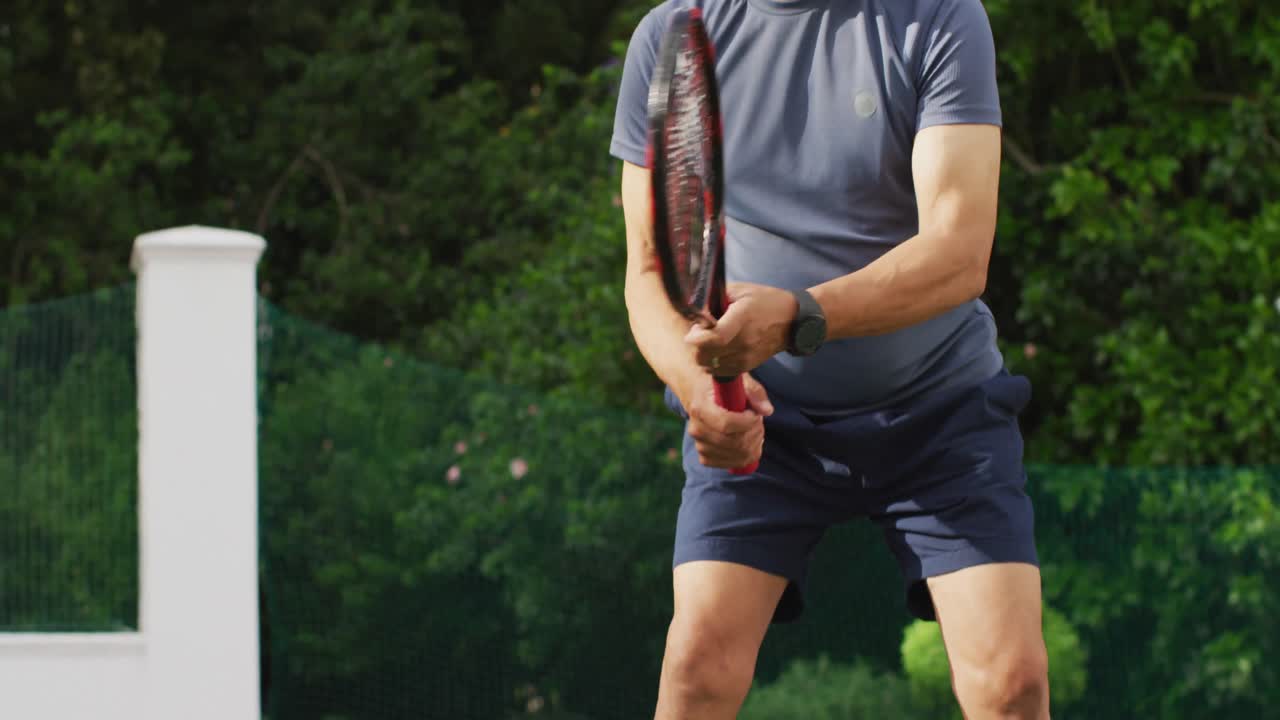 테니스 코트에서 테니스를 하는 초점을 맞춘 두 인종의 노인 남자의 중간 부분의 비디오