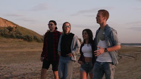 group of young people walking by sandy road near the sea or lake