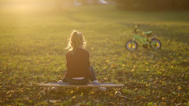 Ragazza seduta su skateboard nel parco