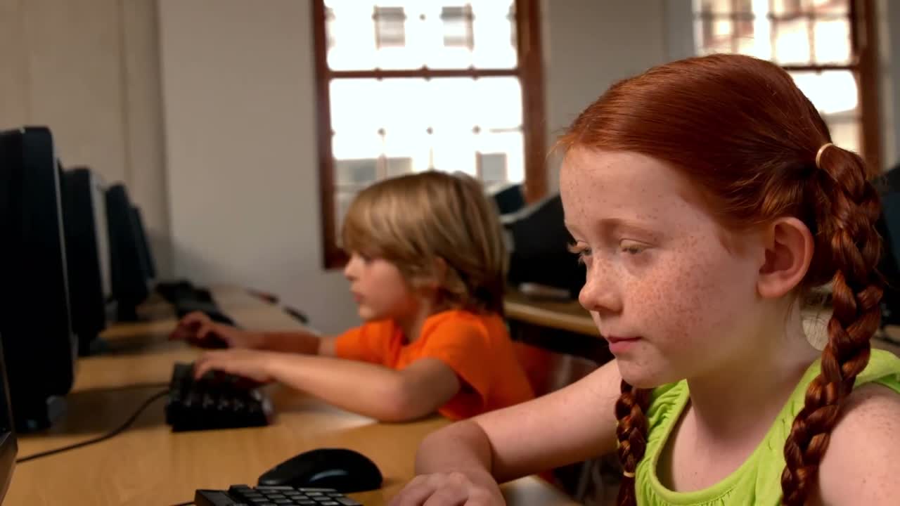 Little girl using computer in classroom in school