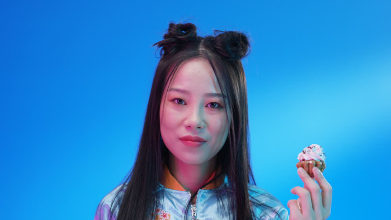 핑크 크림 1 작은 컵 케이크를 먹는 여자의 클로즈업