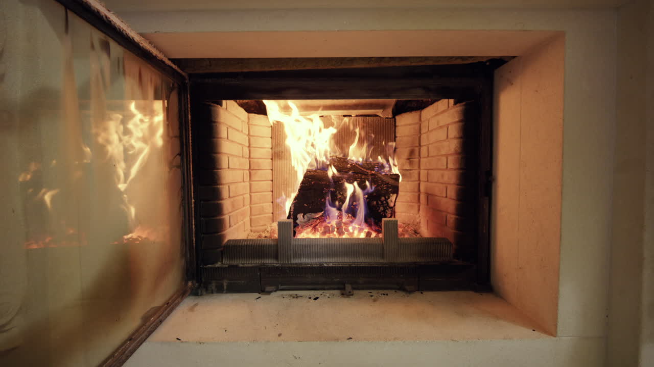 Primer plano de una chimenea encendida con leños ardiendo y llamas visibles.