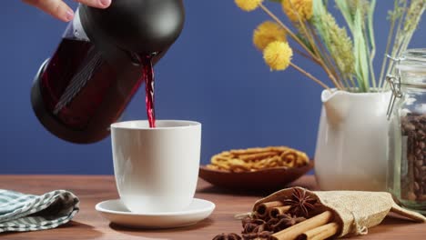 preparando té negro en una tetera de primer plano. bebiendo una bebida herbal caliente sobre un fondo azul