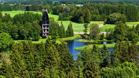 aerial view approaching the canoe-shaped kirkilai observation tower beside vivid karst lakes and lush forests in biržai regional park, lithuania