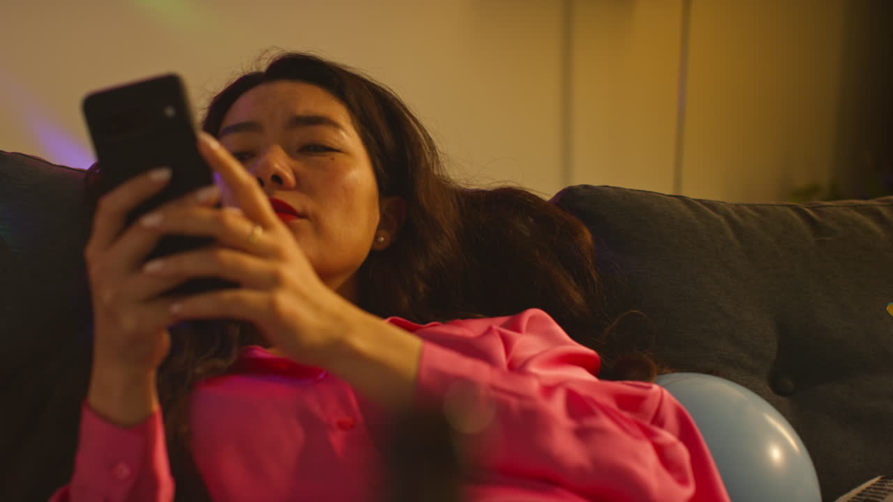 Woman Waking Up On Sofa After Drinking Alcohol At House Party Suffering With Hangover Checking Mobile Phone Messages 3