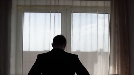 man getting dressed by the window