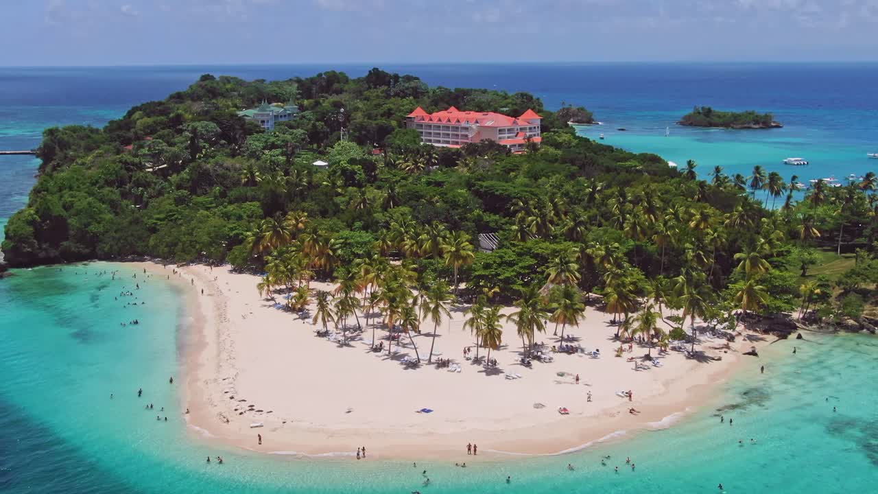 Turisti nuotano nel mare idilliaco dei Caraibi al largo di una spiaggia sabbiosa tropicale di un'isola, ripreso da drone