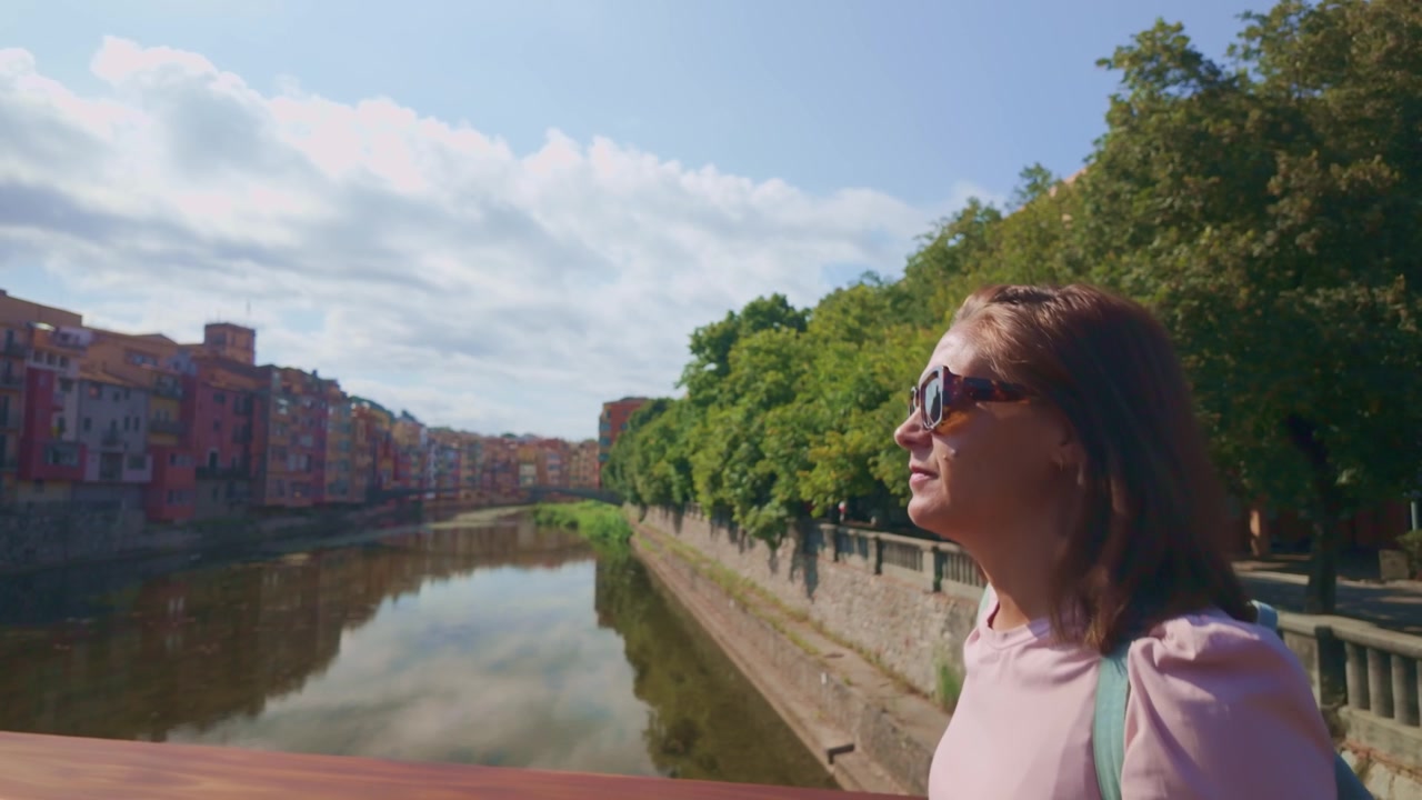 Donna turista che ammira le case colorate che si riflettono sul fiume Onyar a Girona.