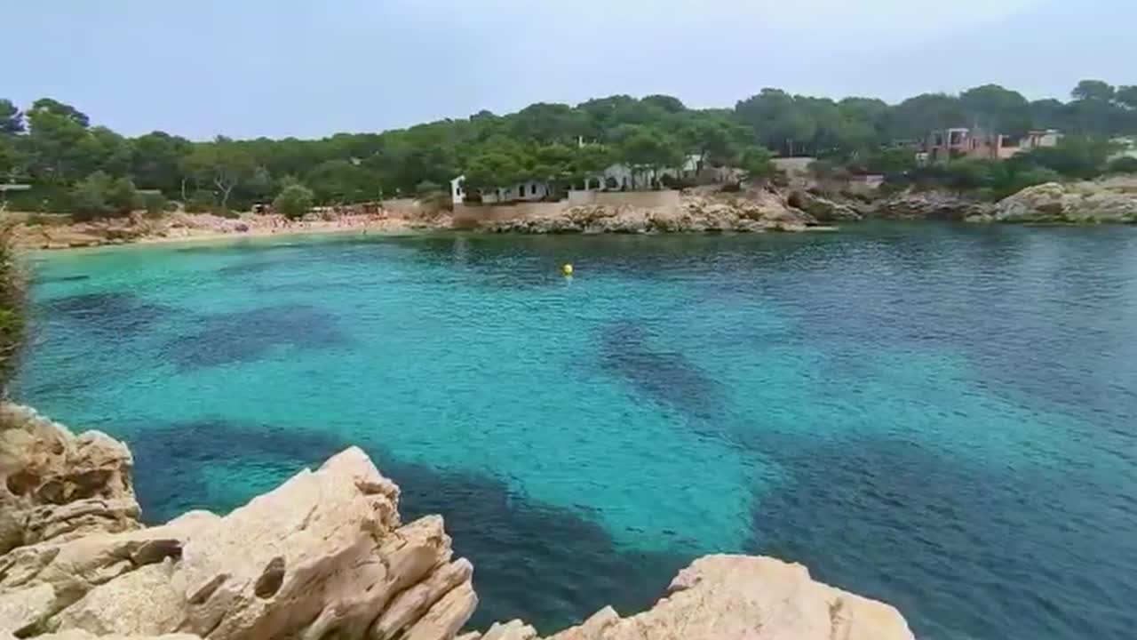 Smuk bugt på Mallorca, Cala Gat i Cala Ratjada, i godt vejr med bøger, en strand og et lille hus.