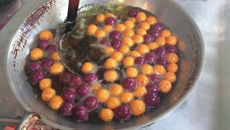 cocinar huevos de caramelo de codorniz o huevos de tortuga dulces en una sartén grande con aceite caliente, bocadillo tradicional tailandés hecho de harina de yuca (almidón de tapioca) y patata dulce en el mercado. imágenes de 4k.