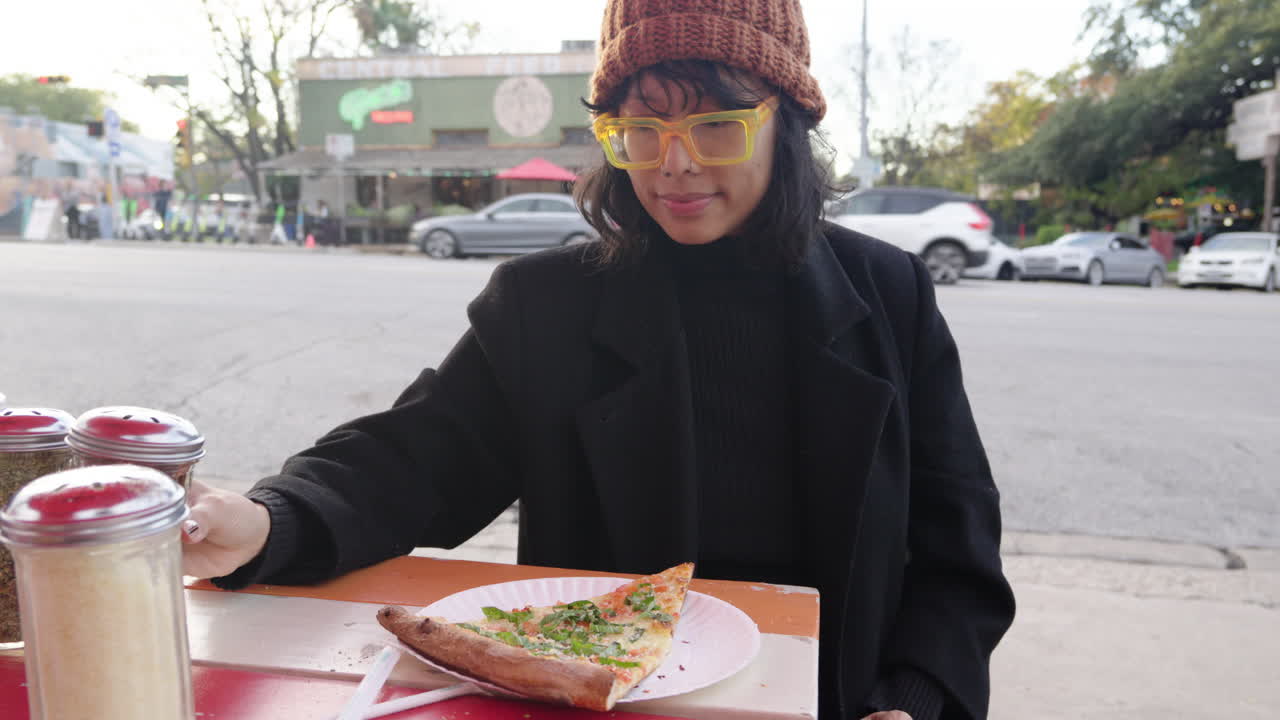 Cute Asian woman putting chili flakes on margherita cheese pizza at outdoor pizza joint on the street