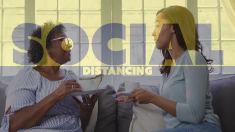 animation of covid 19 social distancing text over two women having tea and talking