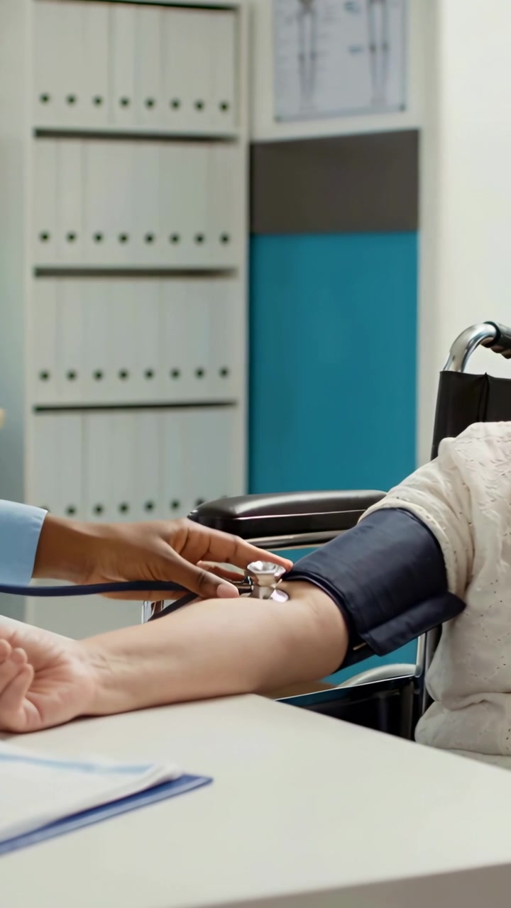 Video verticale: Infermiera che si avvicina in camice, posiziona il bracciale e lo stetoscopio in clinica, gonfiando e registrando la pressione sanguigna