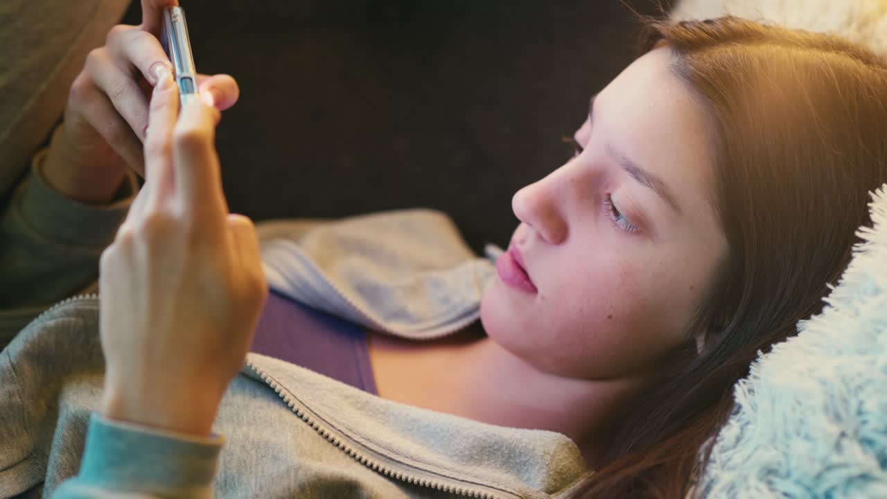 Teenage girl relaxing on a cozy couch, intently using her smartphone. Warm natural lighting enhances the tranquil and casual atmosphere.