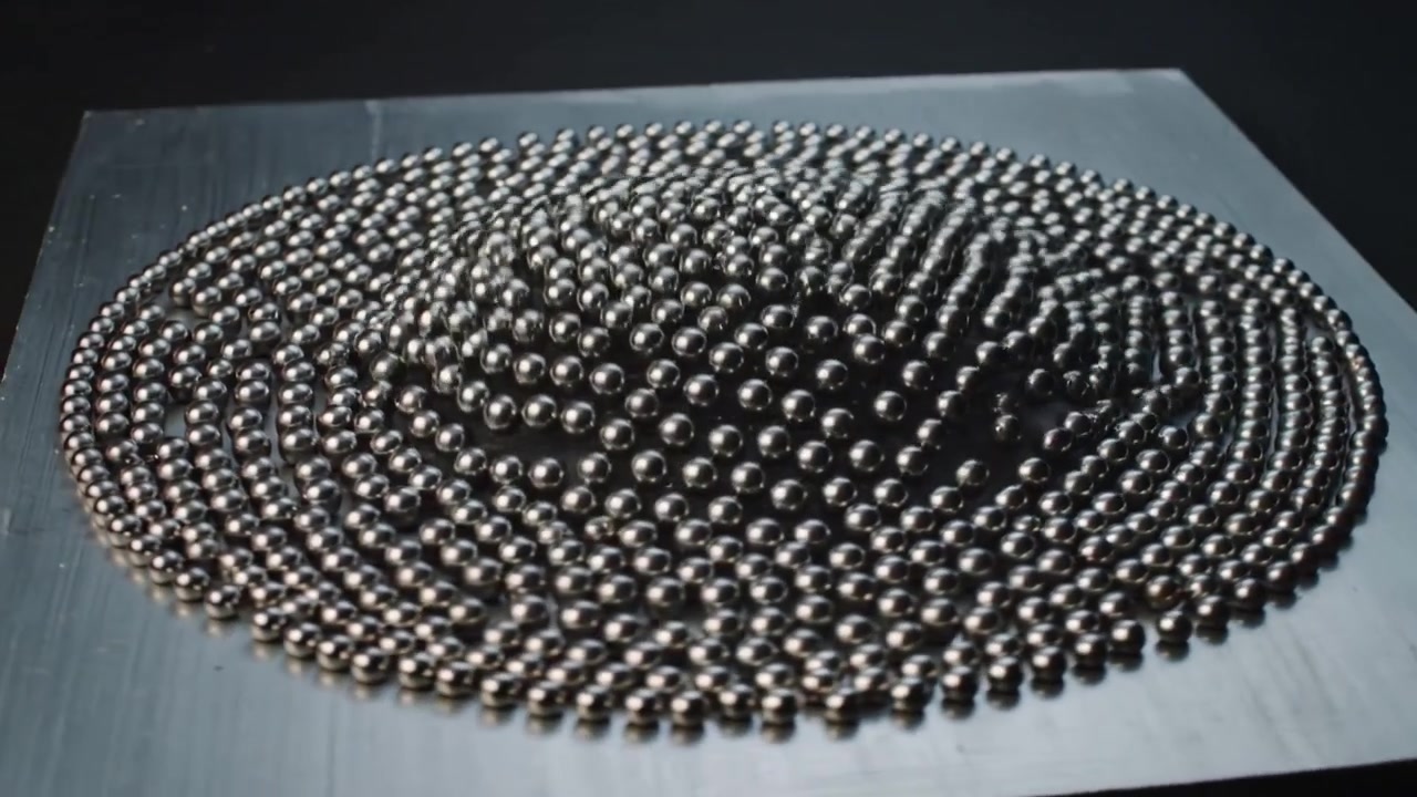 Responding to varying magnetic field under studio plate, steel spheres forming dome and ring ridges