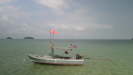 orbiting shot of a small speed boat with a thai flag in ocean with tropical islands