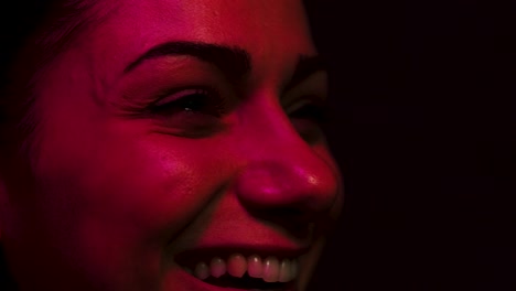 mujer riendo mientras mira una pantalla, ya sea televisión o cine, mientras está iluminada por luz rgb