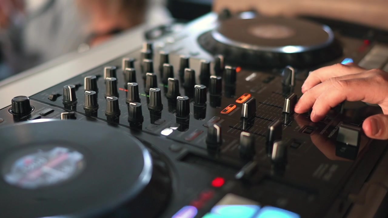 Mani del DJ che regolano manopole e fader su una console di missaggio professionale nera durante una festa pomeridiana con illuminazione naturale. Vista macro dettagliata in primo piano.