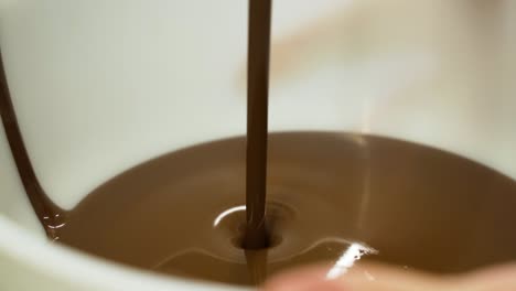 chocolate flowing into bowl, preparation of milk chocolate at cake factory, slow motion