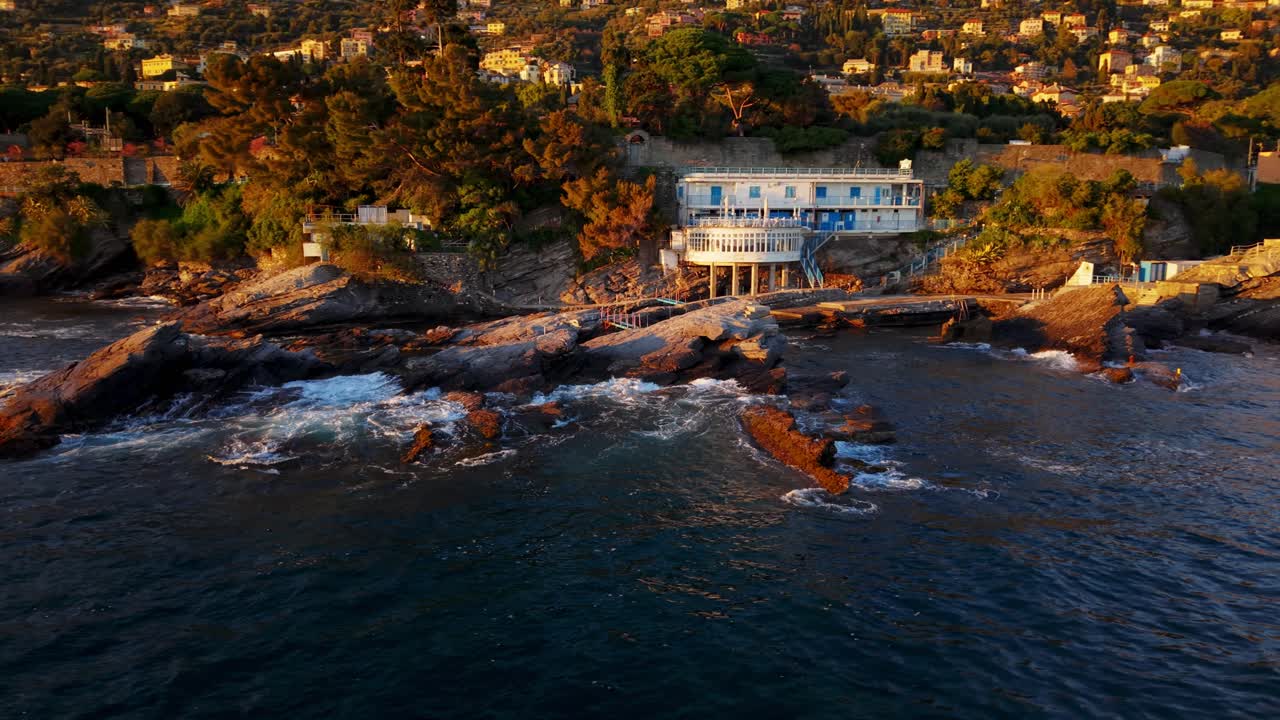 Coastal house on rocky shore in genoa, italy at sunset, aerial view