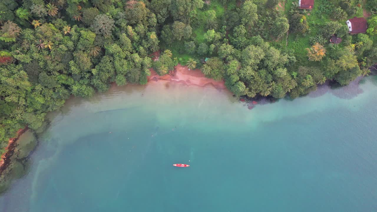 Bird's eye view of houses on the Prince Island coast and a boat anchored offshore, Ilha do Principe,Africa