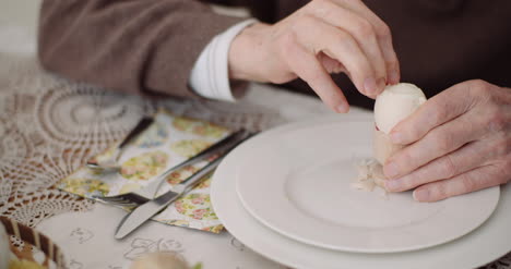 old man peeling egg on plate 1