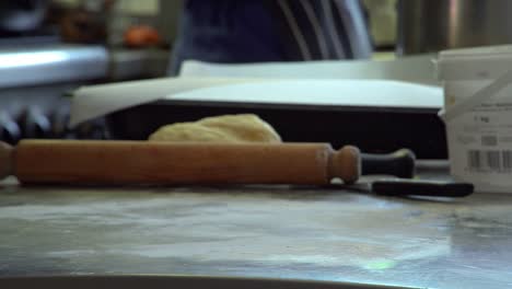 a chef turns over and readjusts a piece thin pastry to continue rolling out