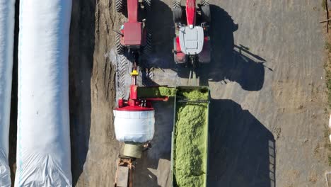 Von-Oben-Nach-Unten-Aufgenommene-Luftaufnahme-Von-Silage,-Die-Zur-Lagerung-Auf-Einem-Amerikanischen-Bauernhof-In-Ein-Weißes-Rohr-Gefüllt-Wird