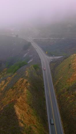 road in the mountains hardly seen through the thick fog. rocky coastline of pacific in montara, california, usa. vertical video