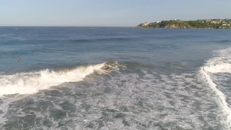 toma aérea de un boogie boarder en una ola de tubo con un arco iris en playa zicatela puerto escondido, oaxaca