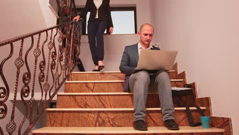ejecutivo de la oficina sentado en la escalera escribiendo en la computadora portátil